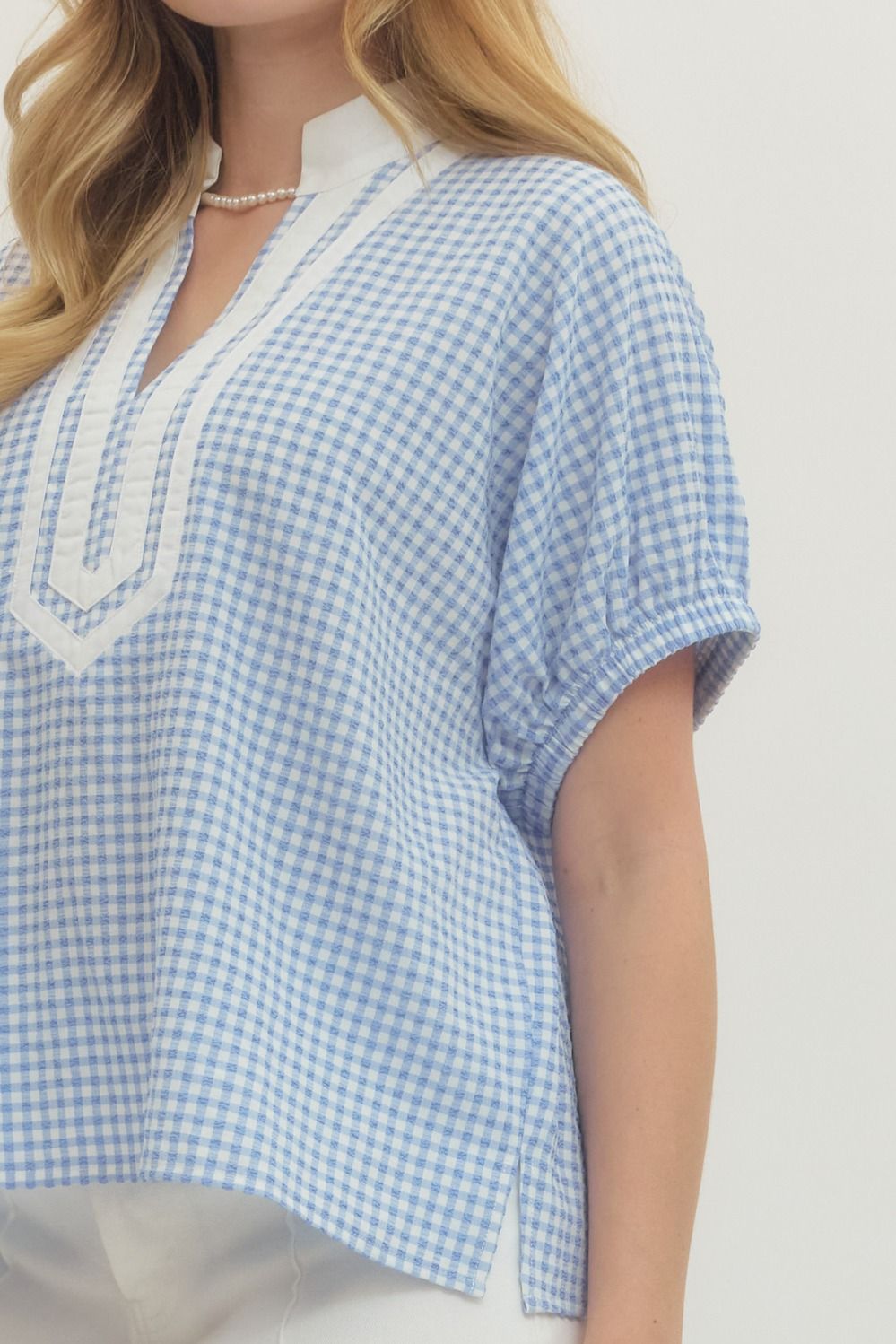 Woman wearing a blue and white checkered top with a plain background