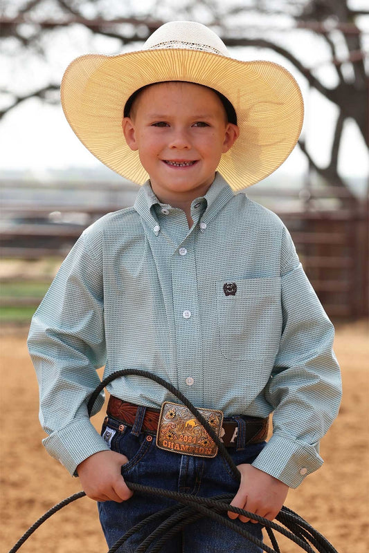 Young boy in cowboy attire holding a lasso outdoors.