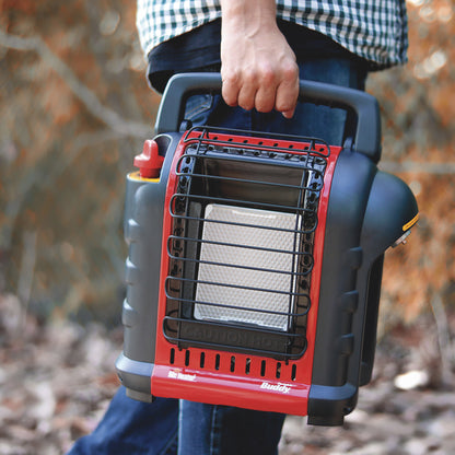 Hand holding portable propane heater outdoors with red and black grill design