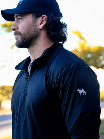 Man wearing a dark blue jacket with a logo on a blurred outdoor background