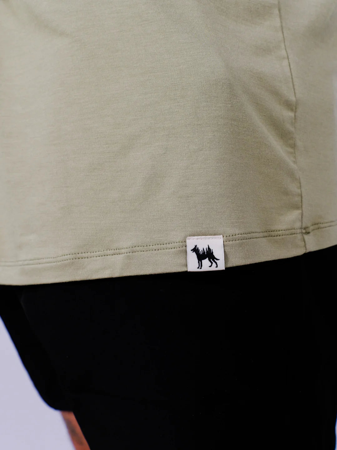 Close-up of a green garment with a brand logo on a light gray background