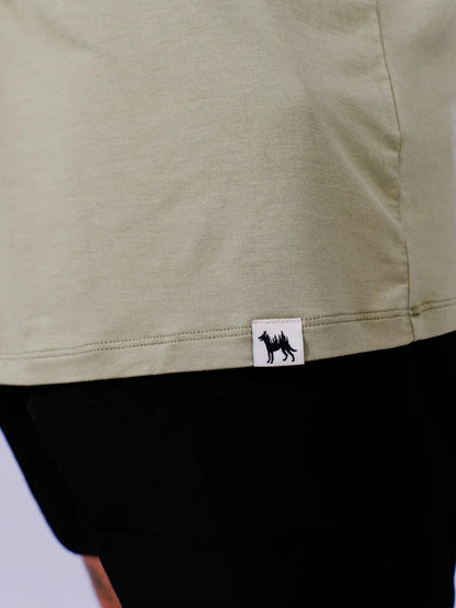 Close-up of a green garment with a brand logo on a light gray background