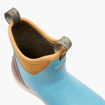 Close-up of a blue waterproof slip-on boot with tan lining and pull tabs, fleece interior